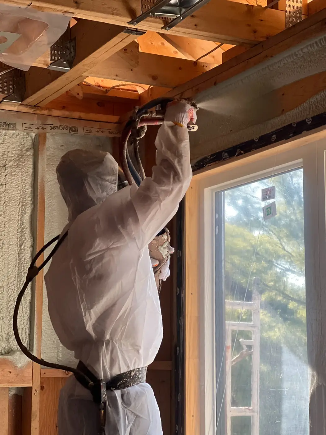 Caliber Certified installer in white protective coveralls spraying 5" (R31) of 2lb closed-cell spray foam on flat ceiling joists in Oshawa & Clarington [JOB-2023-07-22-01]