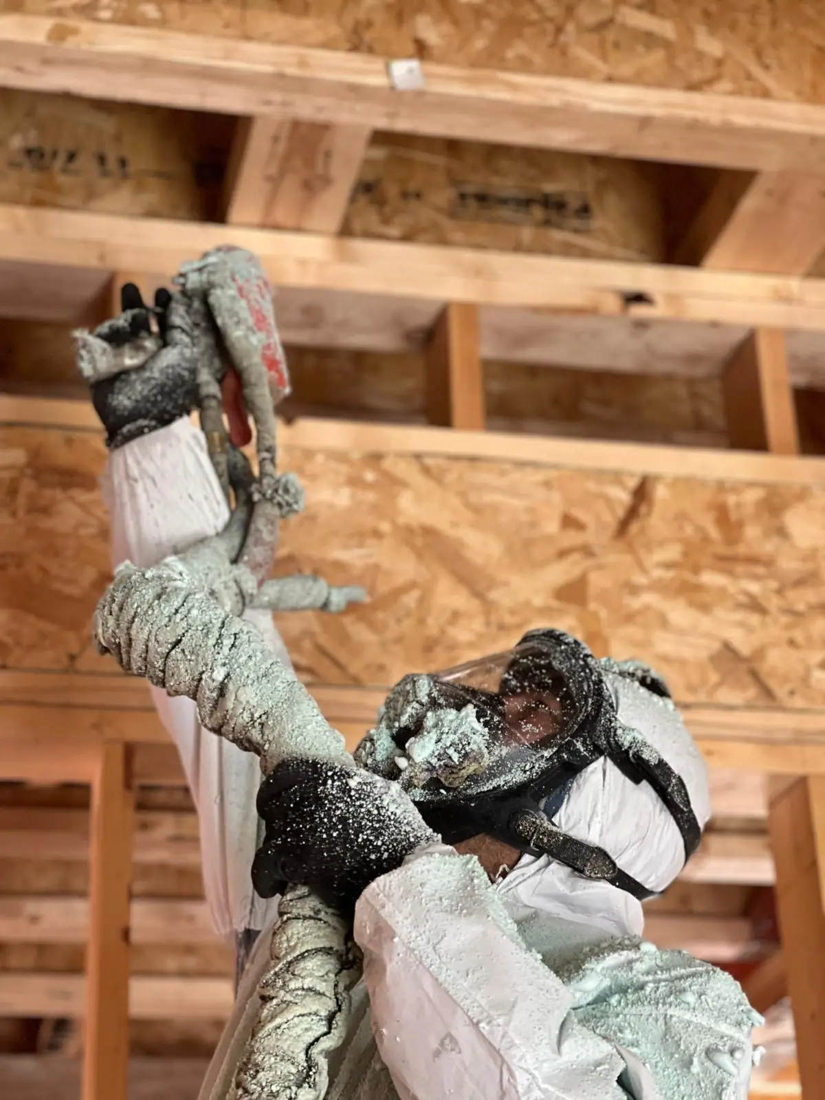 Caliber Certified installer in white protective coveralls spraying 5" (R31) of 2lb closed-cell spray foam on flat ceiling joists in Newmarket & Aurora [JOB-2023-07-22-01]