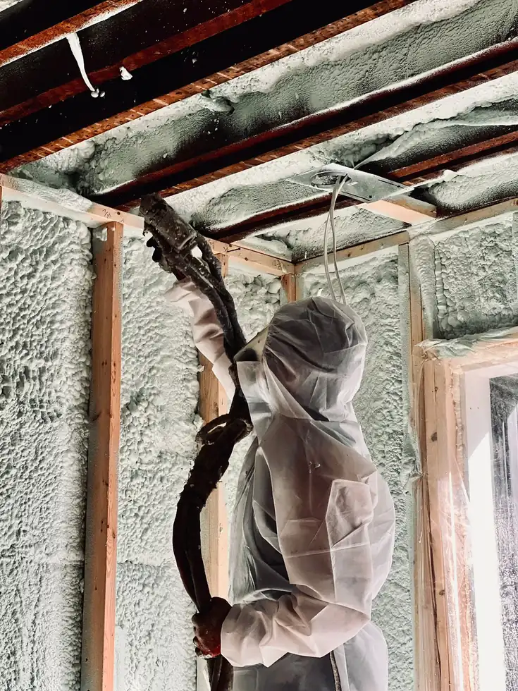 Caliber Certified installer in white protective coveralls spraying 5" (R31) of 2lb closed-cell spray foam on flat ceiling joists and 3.5" (R22) on exterior wall studs in King City & Caledon [JOB-2023-07-22-01]