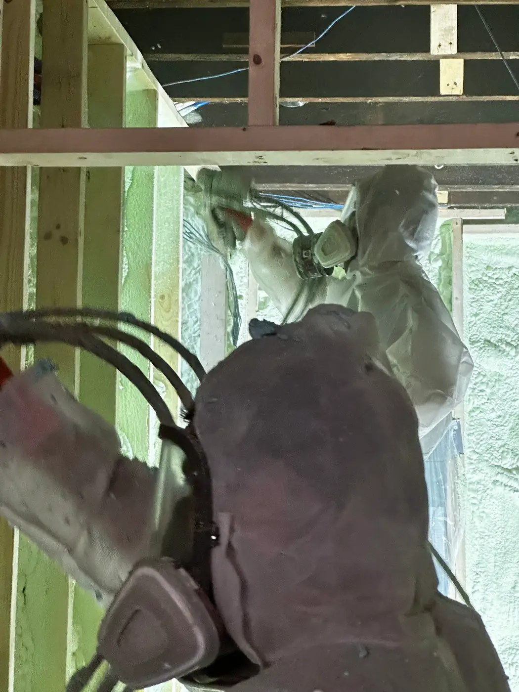 Caliber Certified installer in white protective coveralls spraying 3.5" (R22) of 2lb closed-cell spray foam across exterior 2x6 wood stud cavities in Markham (Unionville & Angus Glen) [JOB-2025-08-09-01]